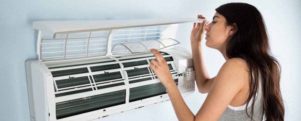 Woman-checking-aircon-for-mold-crop